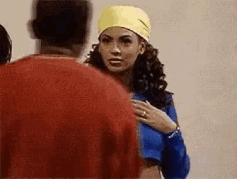 a woman wearing a yellow headband is standing next to a man in a red sweater .