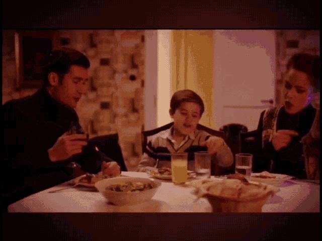 a family sits at a table eating dinner and drinking orange juice