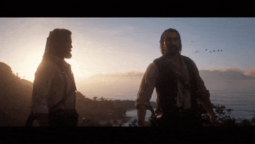 two men standing in front of a body of water