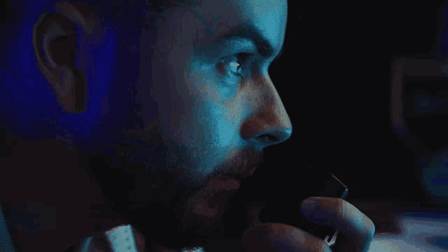a man with a beard is talking on a phone in a dark room