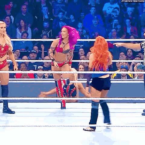 a woman with pink hair is standing in a wrestling ring with other women
