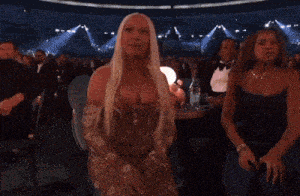 a woman with long blonde hair is sitting in a crowded room