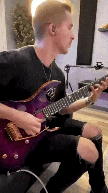 a man is playing a purple electric guitar in a room