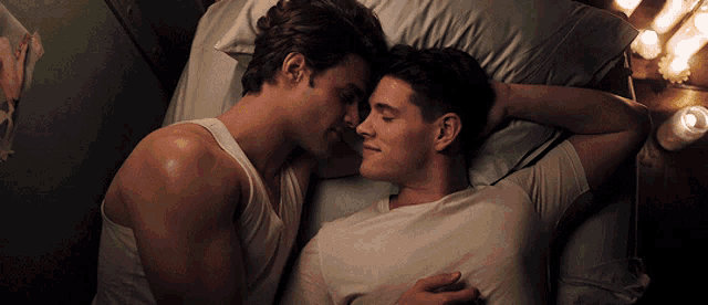 a couple of men laying on a bed with their eyes closed