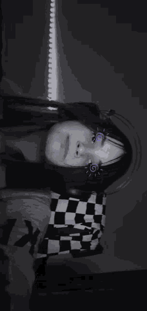 a black and white photo of a girl in a checkered shirt .