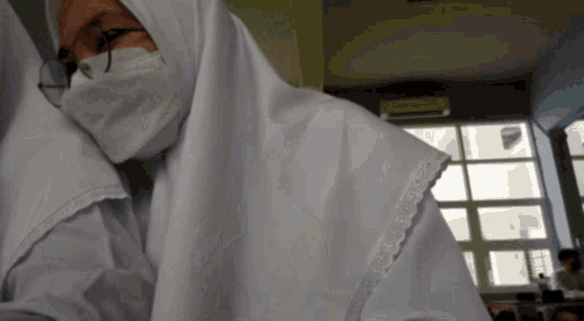 a woman wearing a white hijab and a mask
