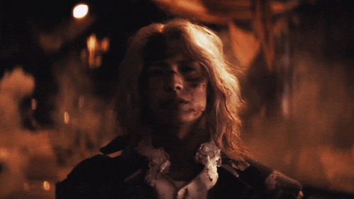 a woman with blonde hair and a lace collar is looking at the camera