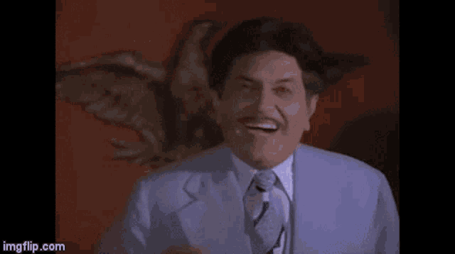 a man in a suit and tie is laughing in front of an eagle on a wall .