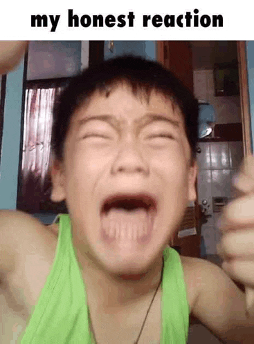 a young boy in a green tank top is crying with his mouth wide open .