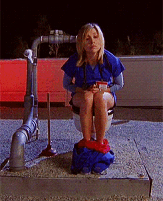a woman sits on a toilet with her pants down and a cup in her hand