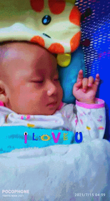 a baby sleeping next to a stuffed animal with the words i love you on it