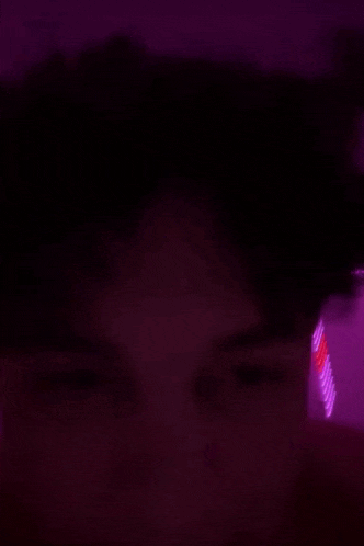 a blurry picture of a person laying on a bed with purple lights on the ceiling .