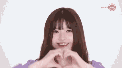 a woman is making a heart shape with her hands .