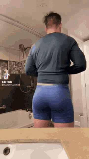 a man in blue boxer briefs is standing in front of a bathroom sink .