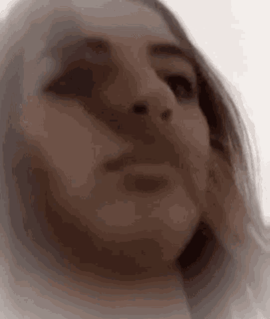 a close up of a woman 's face with her hand on her face and a white background .