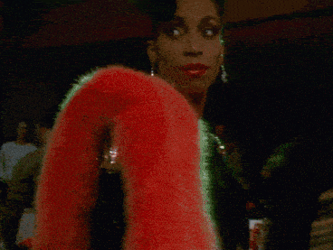 a woman is wearing a black dress and a pink fur coat
