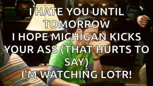 a man in a green shirt is sitting on a couch and says i hate you until tomorrow i hope michigan kicks