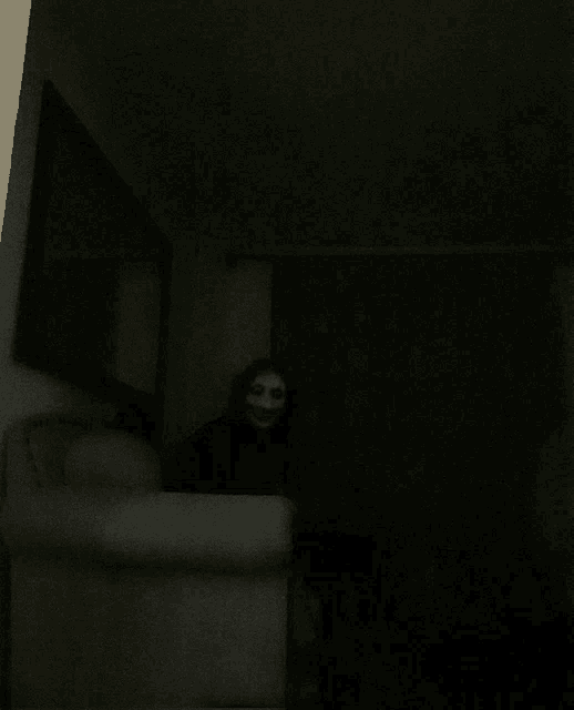 a person in a mask is sitting in a chair in the dark