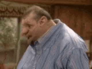 a man in a blue striped shirt is standing in a kitchen .