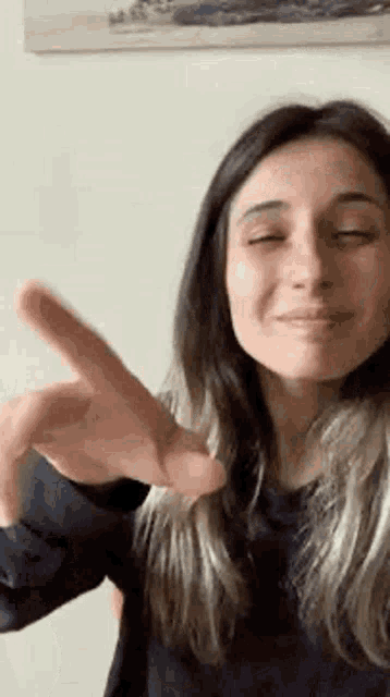 a woman is making a peace sign with her hand in front of her face .