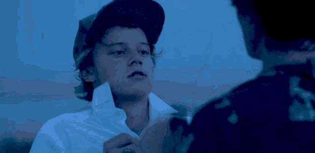 a man in a white shirt wipes his face with a blue cloth