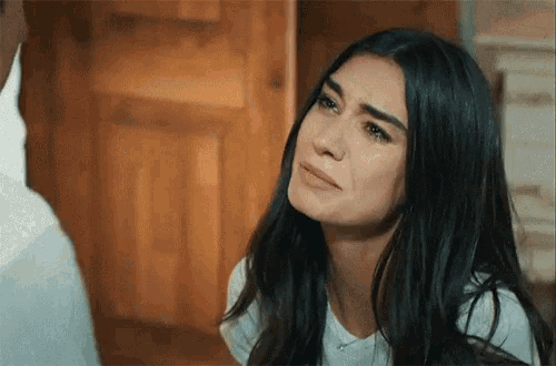 a woman is crying while looking at a man 's face .