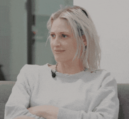 a woman with blonde hair is sitting on a couch and smiling