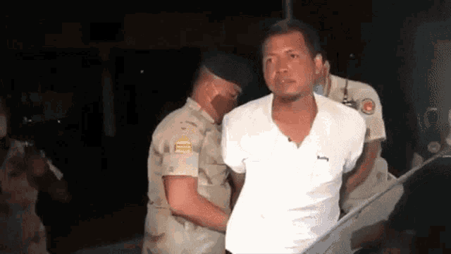 a man in a white shirt is being arrested by police