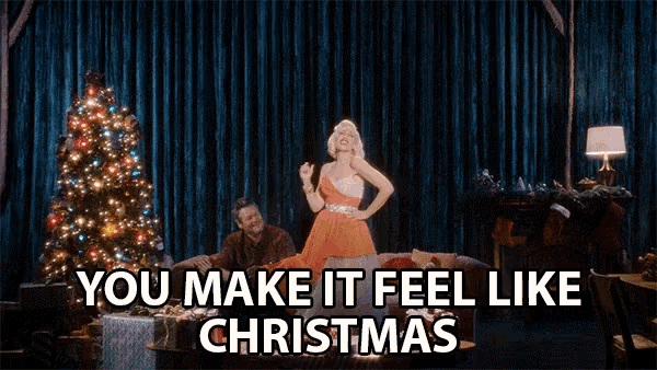 a woman singing in front of a christmas tree with the words you make it feel like christmas below her