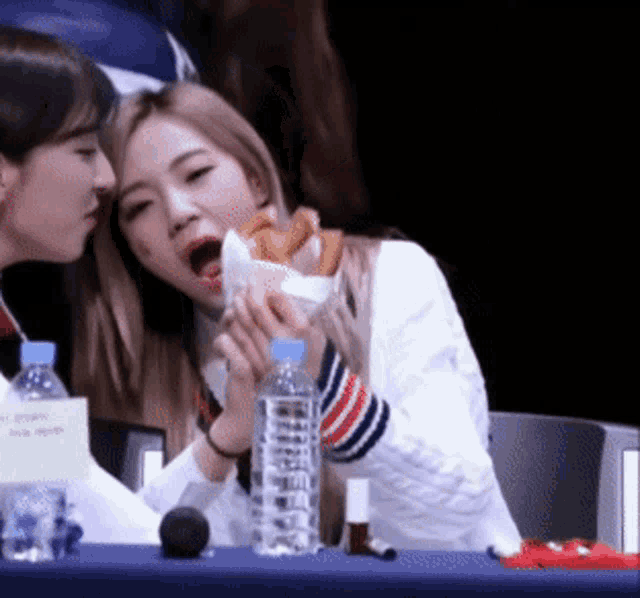 two girls sitting at a table with a bottle of water and a sign that says no smoking