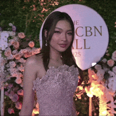 a woman in a pink dress stands in front of a cbn sign