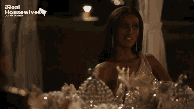 a woman sitting at a table with a real housewives logo on the bottom