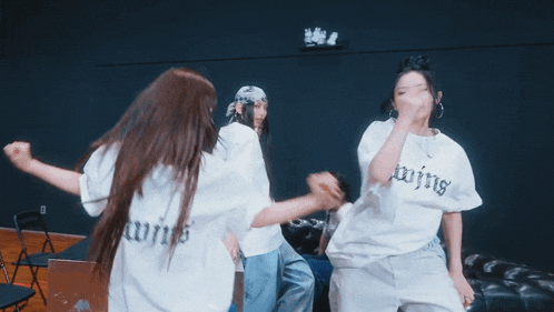 a group of women are dancing in a dark room with a sign that says exit