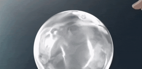 a person is touching a clear glass ball on a dark background