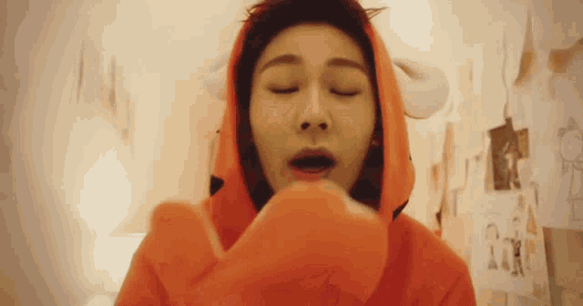 a woman is wearing an orange hoodie with horns on it