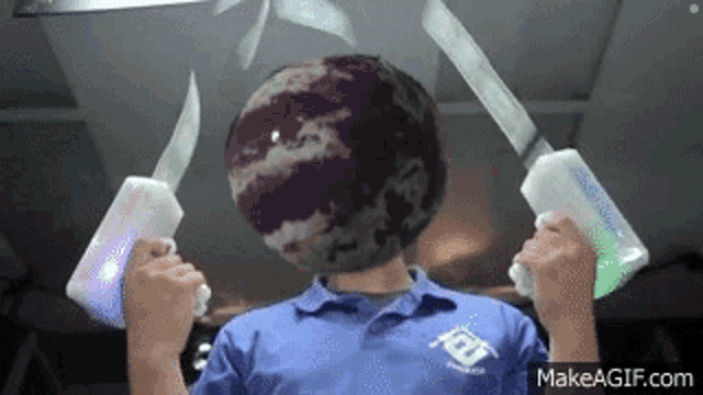 a man is holding a purple ball in front of his head and a pair of knives .