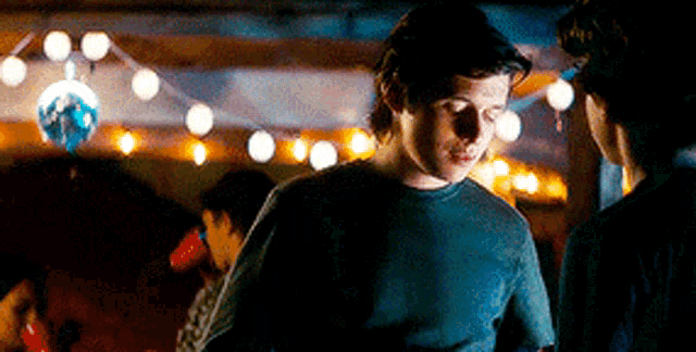 a man in a black shirt is standing in a dark room with a disco ball in the background .
