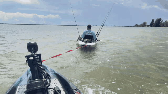 a man in a blue shirt that says ' fishing ' on it is pulling a kayak