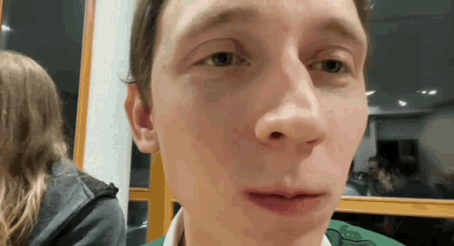 a close up of a man 's face with a woman behind him