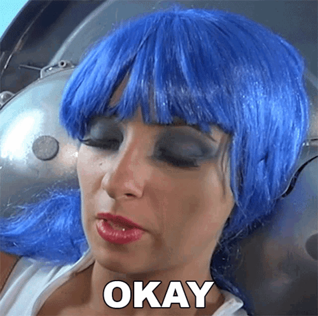 a woman wearing a blue wig has the word okay on her face