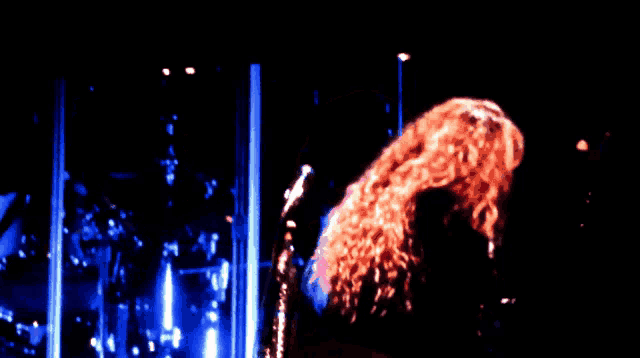a woman stands in front of a microphone in a dark room