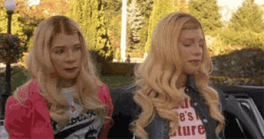 two blonde women are sitting in a car .