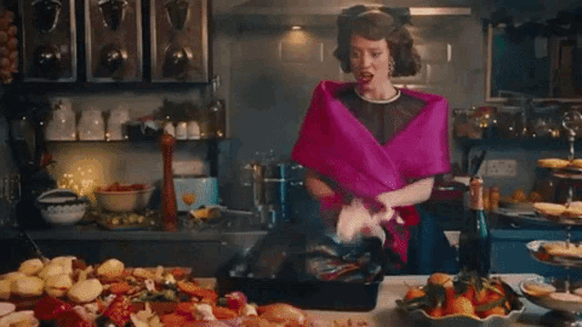 a woman in a pink shawl is cooking a turkey in a pan