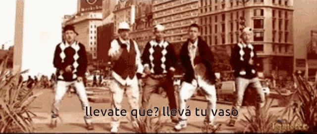 a group of men are dancing on a street with the words llevate que on the bottom right