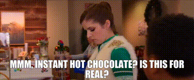 a woman is standing in a kitchen with the words instant hot chocolate is this for real written below her