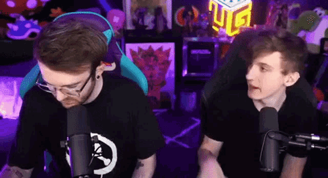 two boys are sitting in front of microphones in a room .