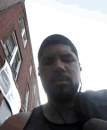 a man wearing headphones stands in front of a building with a sign that says " buy "