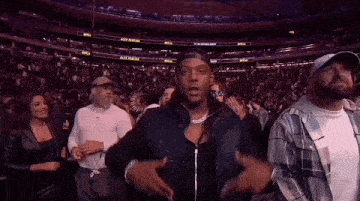 a man is standing in front of a crowd of people at a basketball game .