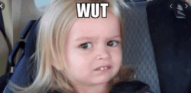 a little girl is sitting in a car seat and making a funny face with the word wut on her face .