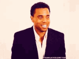 a man in a black suit and white shirt smiles